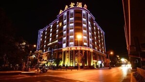 Un hotel de varios pisos con fachada curva y señalización iluminada.