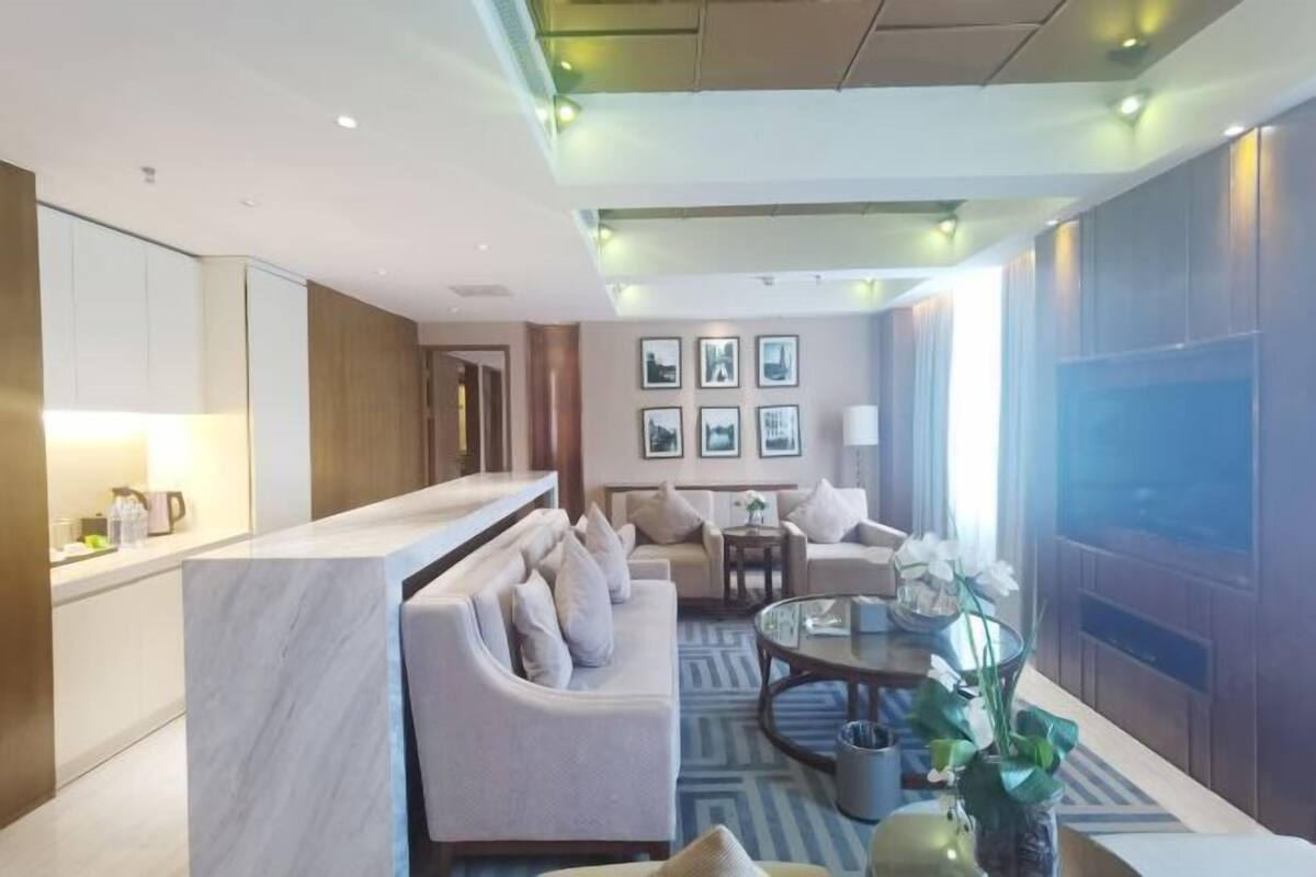 A modern hotel lobby with a marble reception desk, a sofa, a coffee table, and framed pictures on the wall.