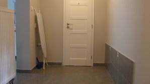 A narrow hallway with a white door, a radiator, and a towel rack. - Alisa Apartments (Kostomlaty nad Labem)