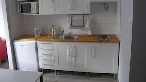A compact kitchen with white cabinets, a microwave, a coffee maker, and a sink. - Alisa Apartments (Kostomlaty nad Labem)
