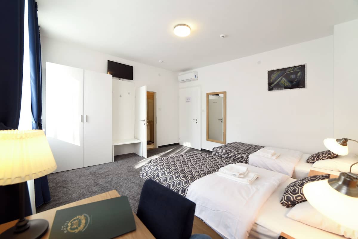 Habitación de hotel con cama, mesita de noche, lámpara, silla, escritorio y lámpara de escritorio.