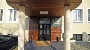 A hotel entrance with a black door, a wooden canopy, and a beige wall. - Hotel Orient Zagreb (Zagreb)