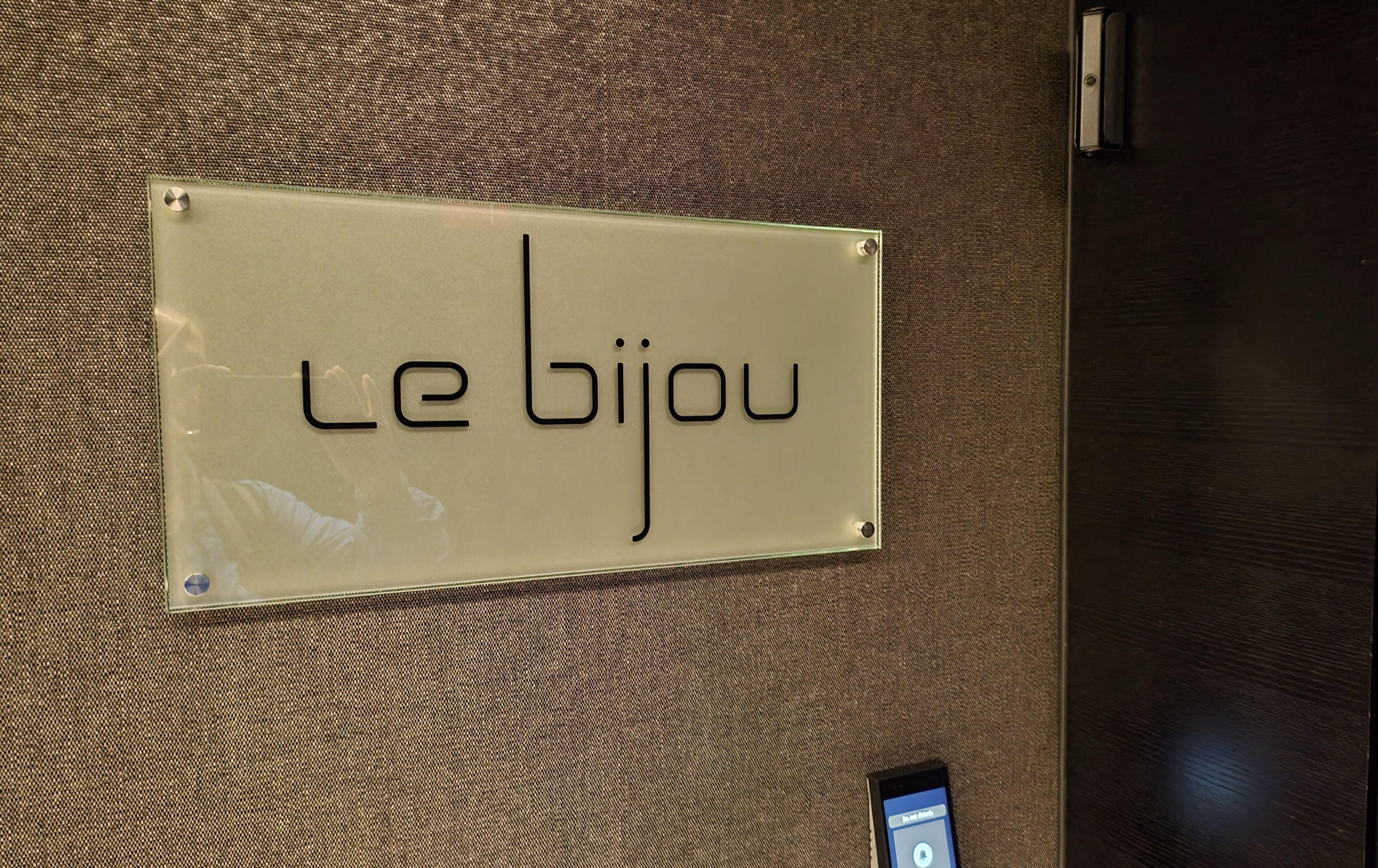 Et skilt med teksten "Le Bijou" på en struktureret væg.