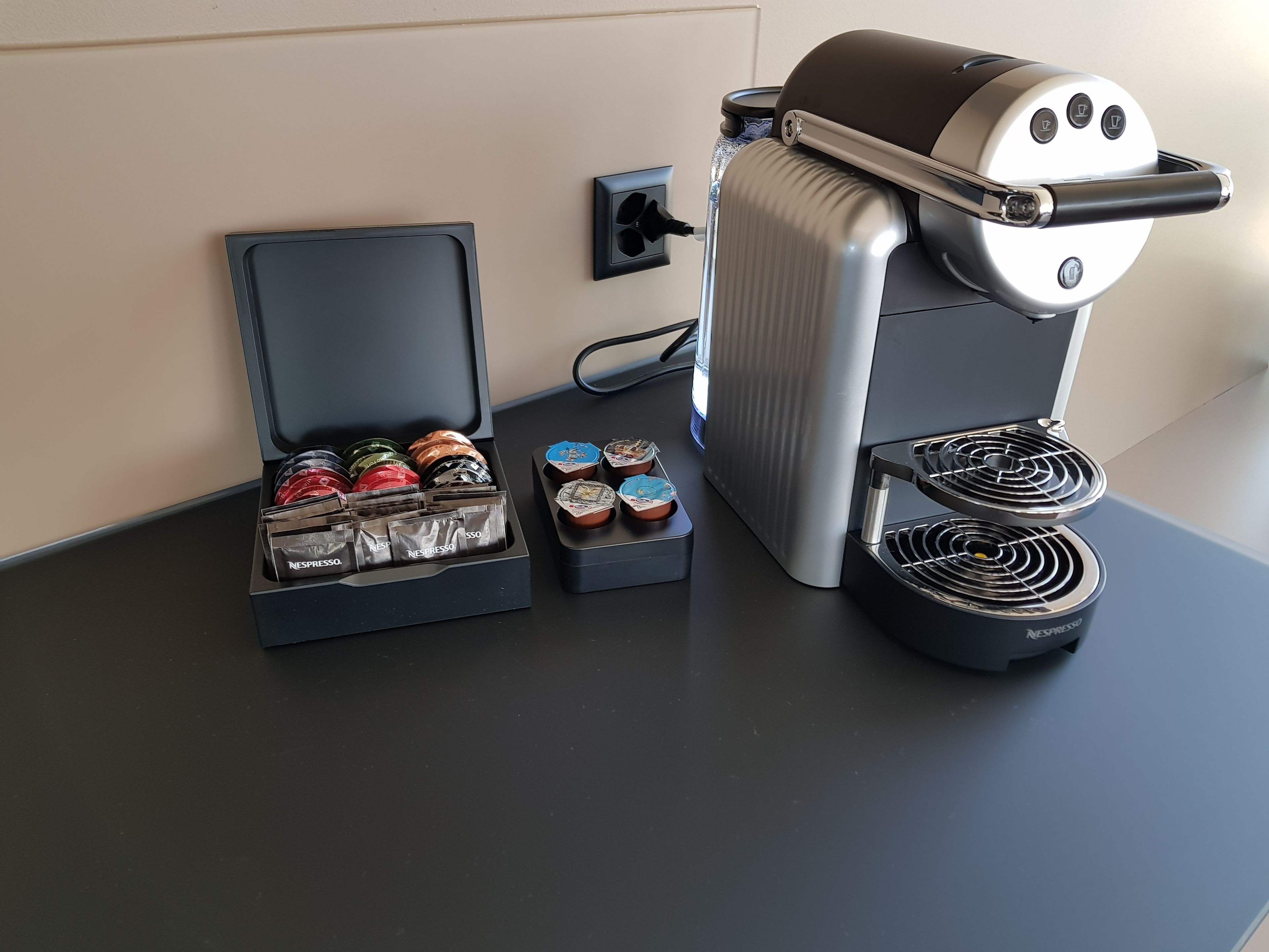 Une machine à café dotée d’un bac de récupération, d’un support pour capsules de café et d’un système de préparation du café.