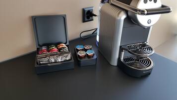 Une machine à café dotée d’un bac de récupération, d’un support pour capsules de café et d’un système de préparation du café.