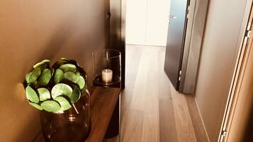 A hallway with a wooden bench, a potted plant, a glass candle holder, and a door.