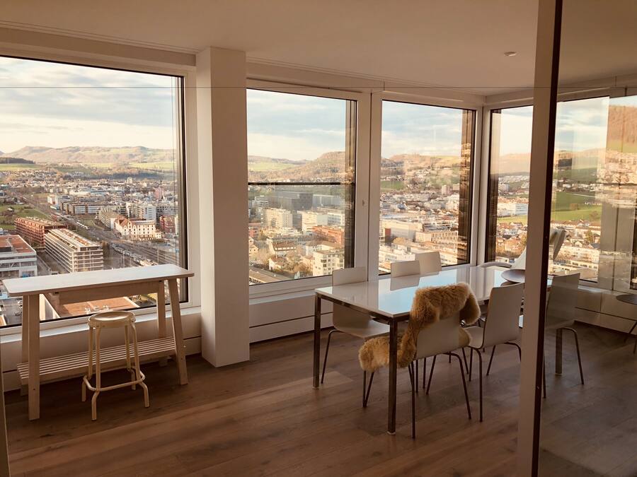Una habitación moderna con ventanas amplias, una mesa de comedor y sillas.