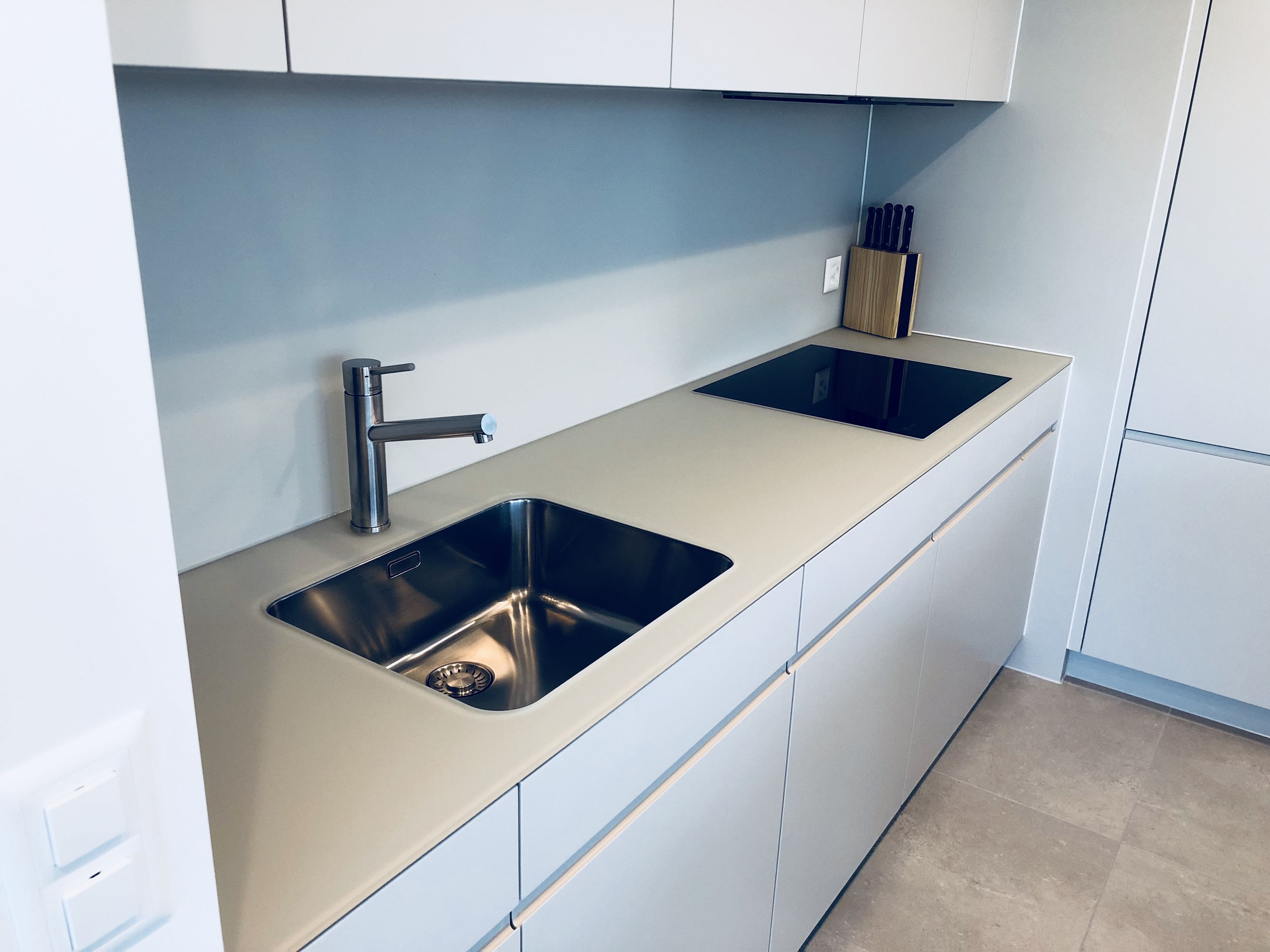 Una cocina moderna con un lavamanos de acero inoxidable, un grifo y un bloque de cuchillos.