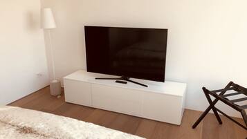 A modern room with a flat-screen TV on a white cabinet, a lamp, and a wooden floor.