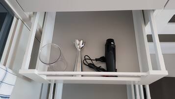 Un cajón con un secador de pelo, un enchufe y una herramienta metálica.
