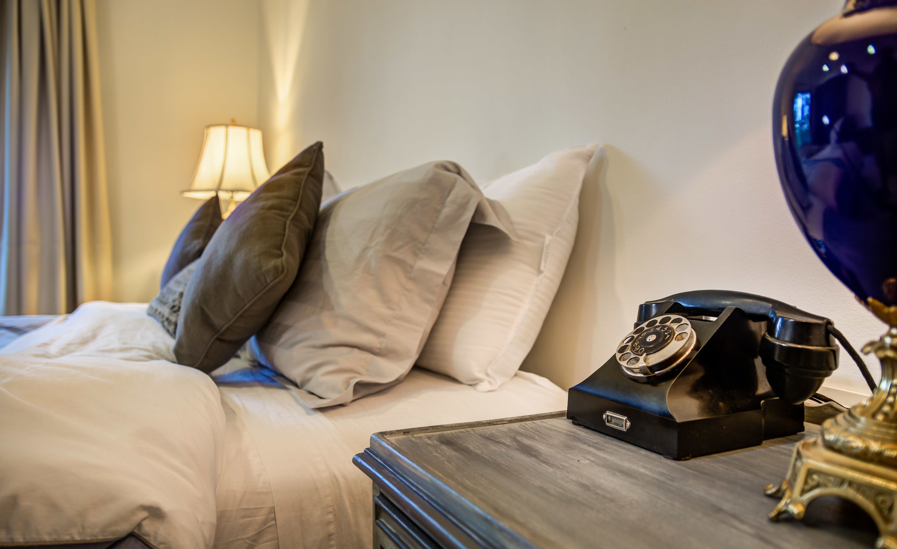 Un lit bien fait, avec un oreiller, une table de chevet sur laquelle se trouve un téléphone et une lampe.