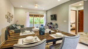 A dining area with a wooden table set for four, a sofa, and a TV mounted on the wall. - El Cielo 1BRM Penthouse private roof sleeps 3 (Tulum)