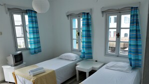 A room with two single beds, a small desk, a television, and windows with curtains. - Palma Hotel (Bodrum)
