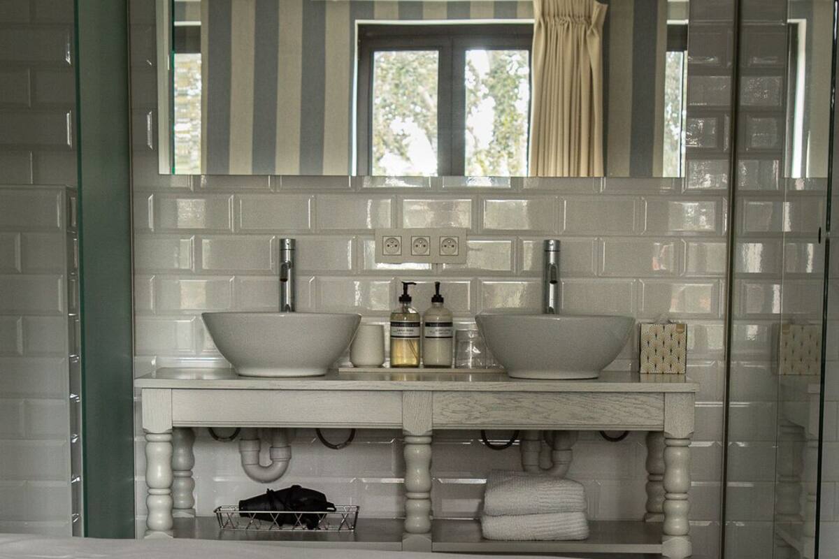 Une salle de bain moderne avec deux lavabos, un grand miroir et un porte-serviettes.