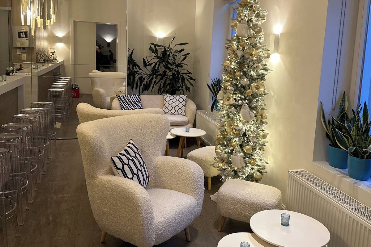 Un intérieur moderne avec des fauteuils confortables, un grand sapin de Noël et un coin bar avec des tabourets.