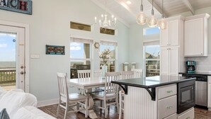 A modern kitchen with white cabinetry, a central island with a black countertop, and pendant lighting.