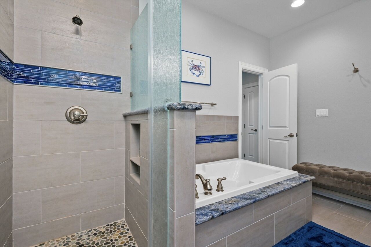 Une salle de bain moderne dotée d’une baignoire sur pieds, d’un espace douche avec une cabine en verre et d’une porte donnant sur une autre pièce.