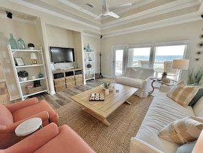 A living room with a flat-screen TV, a coffee table with decorative items, a sofa, and a view of the ocean. - A La Playa 2 Bedroom Home by RedAwning (Port Bolivar)