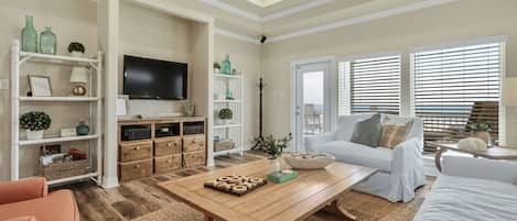 A living room with a television, white sofa, wooden coffee table, and a bookshelf.