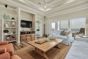 A living room with a television, white sofa, wooden coffee table, and a bookshelf. - A La Playa 2 Bedroom Home by RedAwning (Port Bolivar)