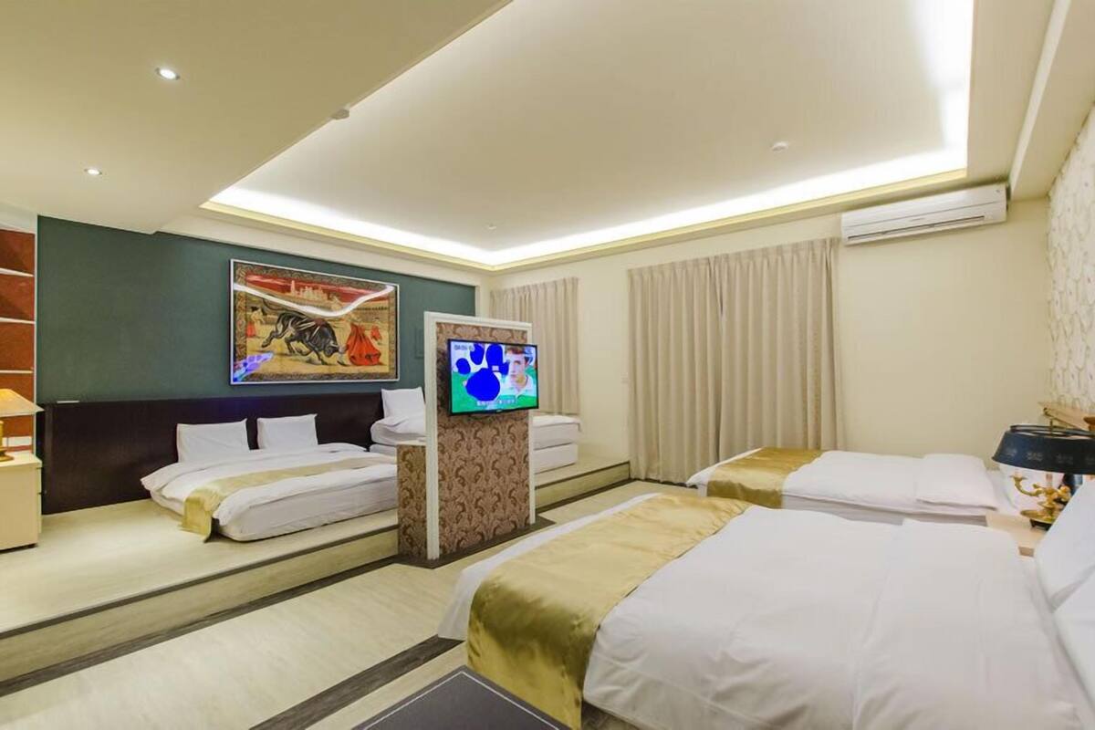 A hotel room with two beds, a TV, and a painting on the wall.