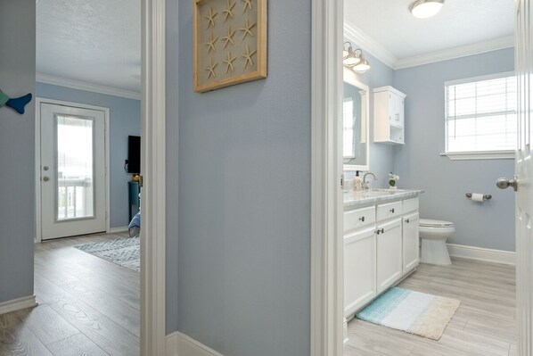 Une salle de bain avec des toilettes blanches, un lavabo avec un miroir et une fenêtre.