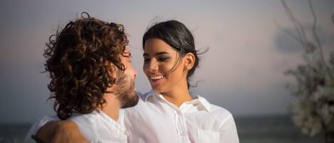 A couple embracing with a beach view in the background.