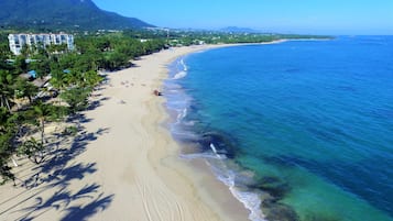 Na praia, areia branca, espreguiçadeiras, guarda-sóis