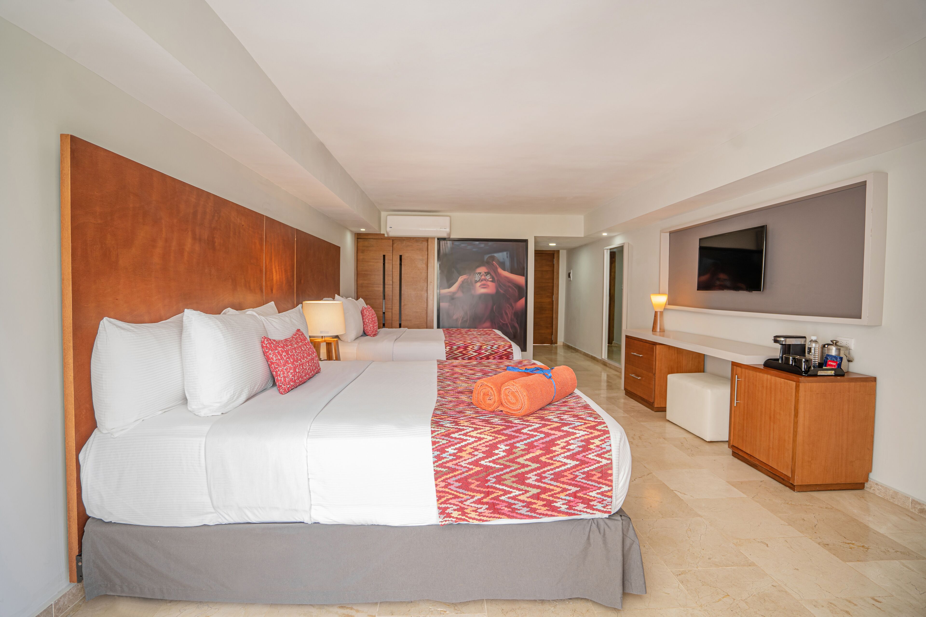 A hotel room with a large bed, a desk, a television, and a bathroom visible through an open door.