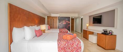 A hotel room with a large bed, a desk, a television, and a bathroom visible through an open door.