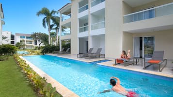 Una piscina con sillas de descanso y un edificio con balcones.