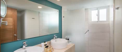 A modern bathroom with two sinks, a large mirror, and a shower area.