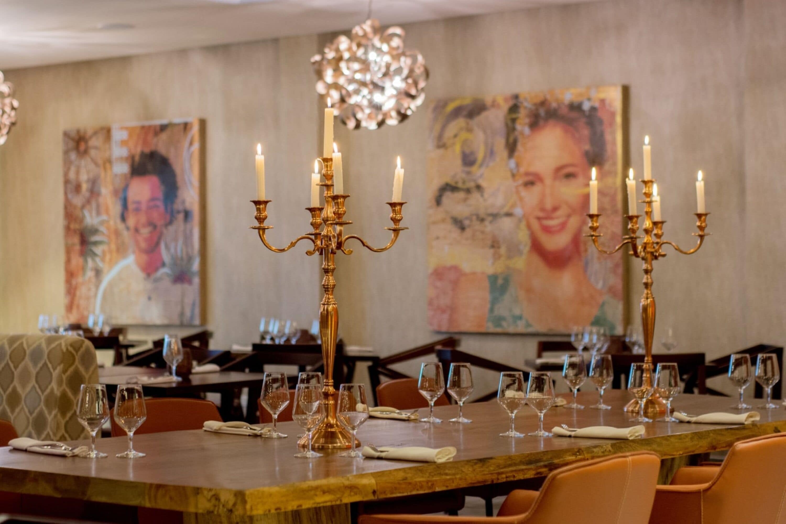 A dining area with tables set for a meal, featuring candelabras with lit candles.