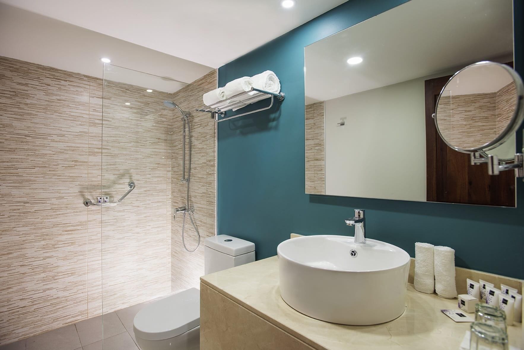 A modern bathroom with a glass-enclosed shower, a white sink, and a large mirror.