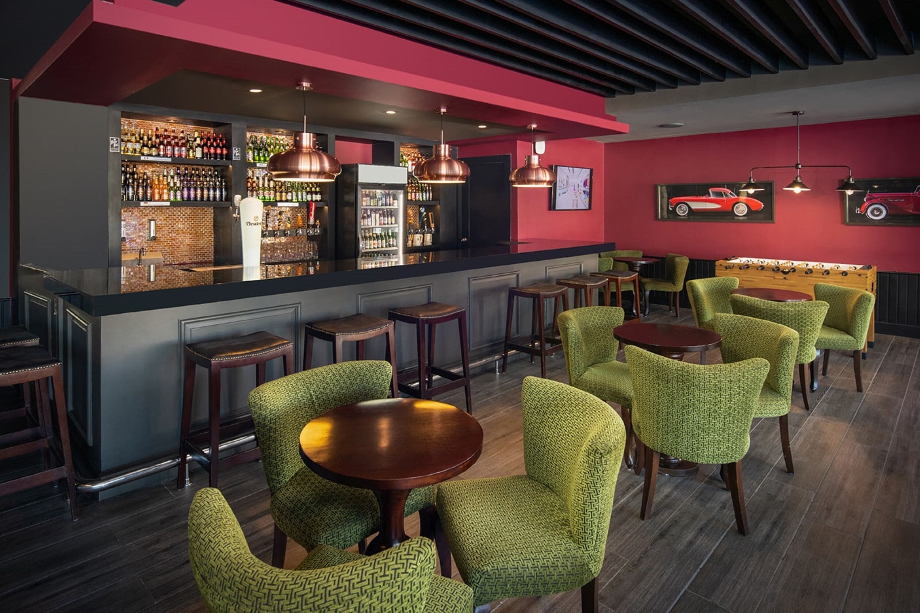 A bar area with a counter, shelves of bottles, and a foosball table.
