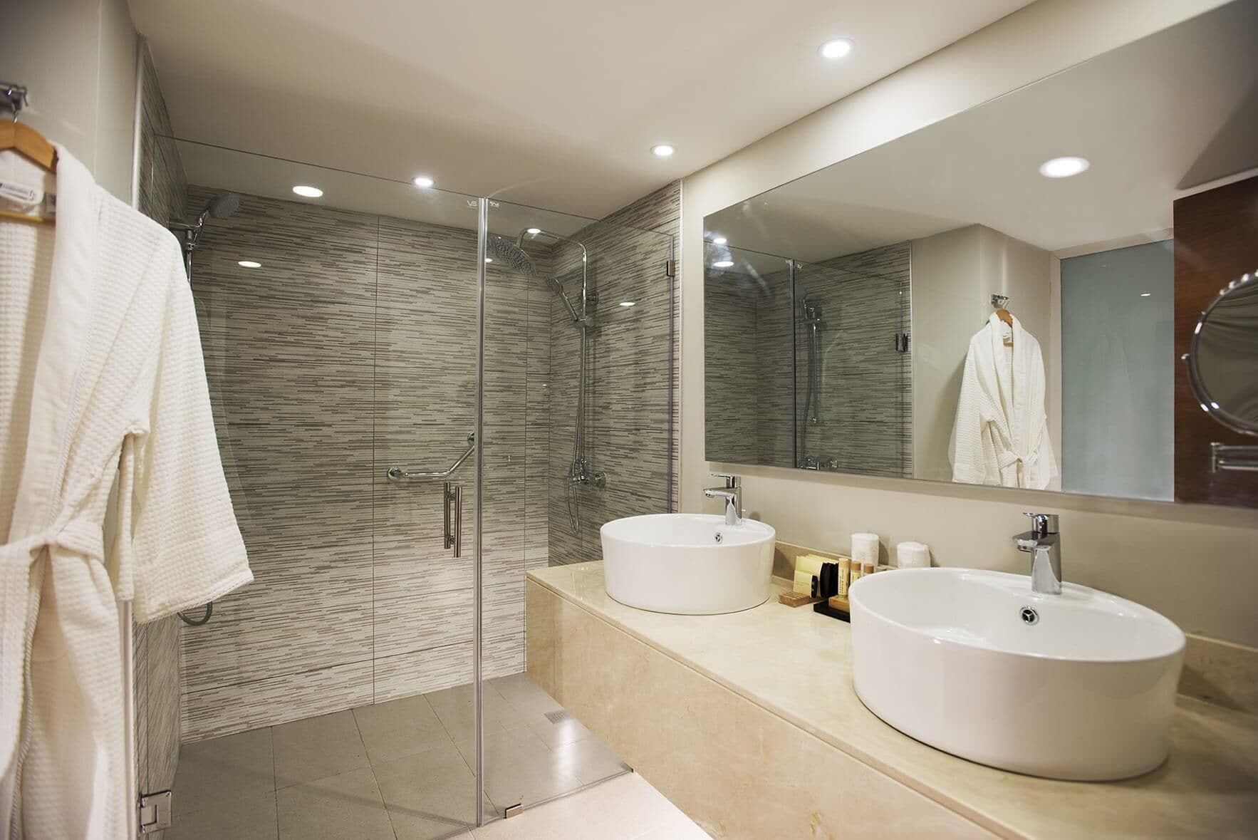 A modern bathroom with a glass-enclosed shower, two sinks, and a large mirror.