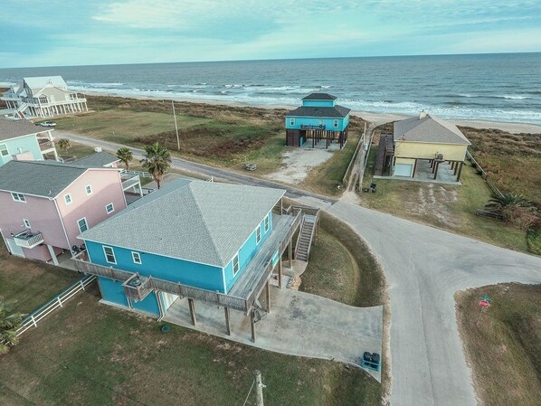 Vista aérea de una zona residencial costera con casas, una carretera y el océano al fondo.