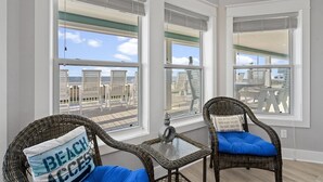 Ein Balkon mit Korbstühlen, einem Glastisch und Blick auf den Strand.