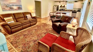 A living room with a brown sofa, a patterned rug, and a wicker chair.