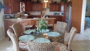 A modern kitchen with wooden cabinets, a central island, and a ceiling fan. - The Sandy Cork 4 Bedroom Home by RedAwning (Port Bolivar)