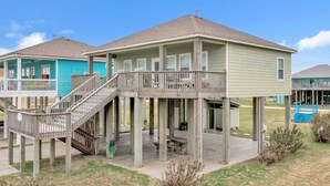 Une maison à deux étages dotée d’une terrasse en bois et d’un patio couvert.