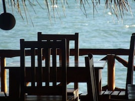 Terraza de madera con sillas y mesas dando a un cuerpo de agua.