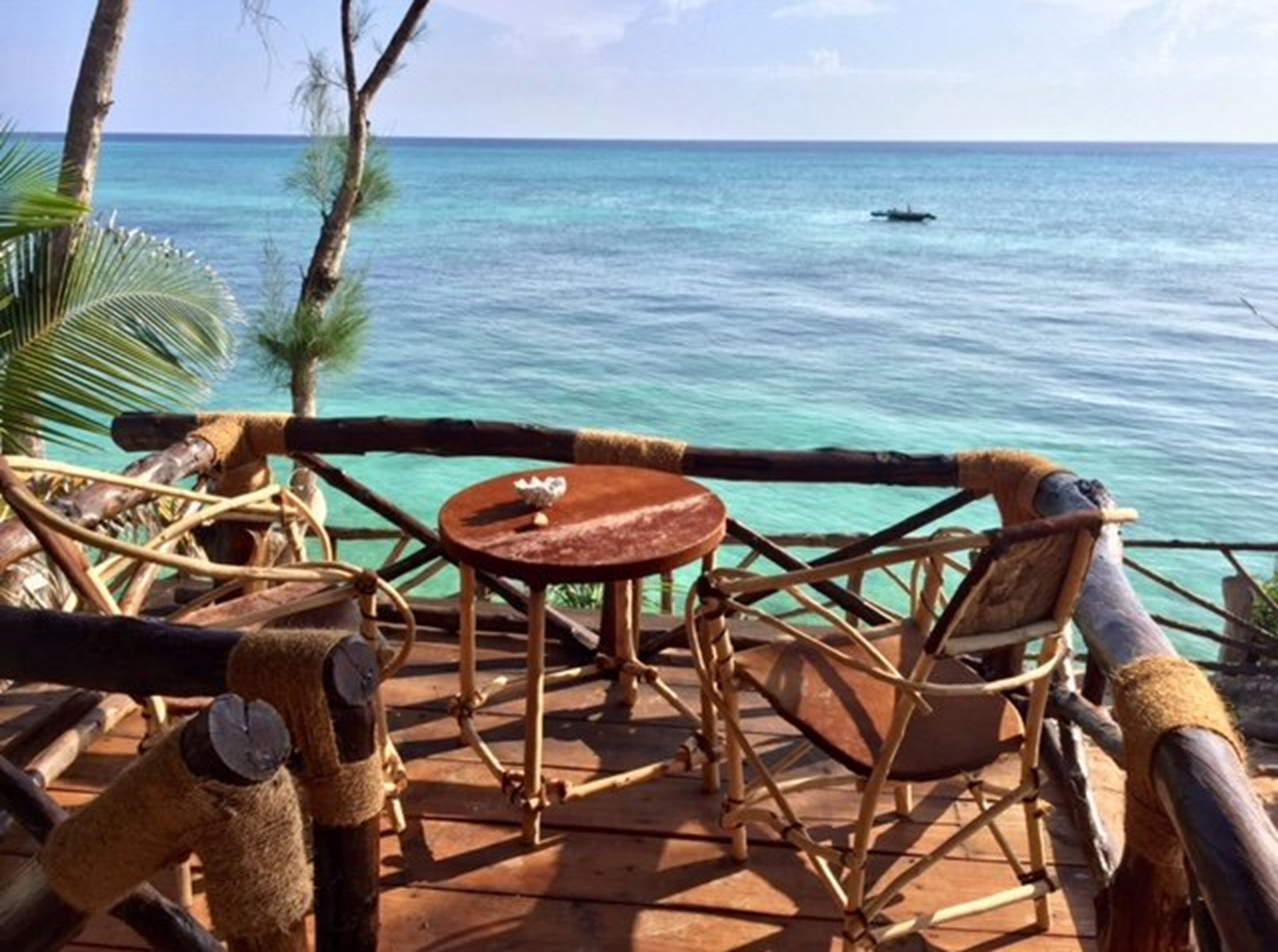 Une terrasse en bois avec une table et des chaises, donnant sur une mer turquoise.