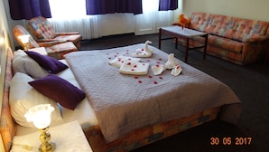 Una habitación de hotel con cama, dos sillones, un sofá, una mesita y una lámpara.