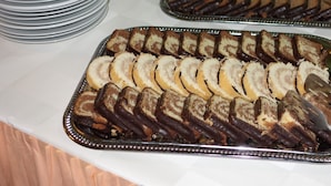 Una mesa de buffet con bandejas de pasteles en rodajas y una pila de platos.