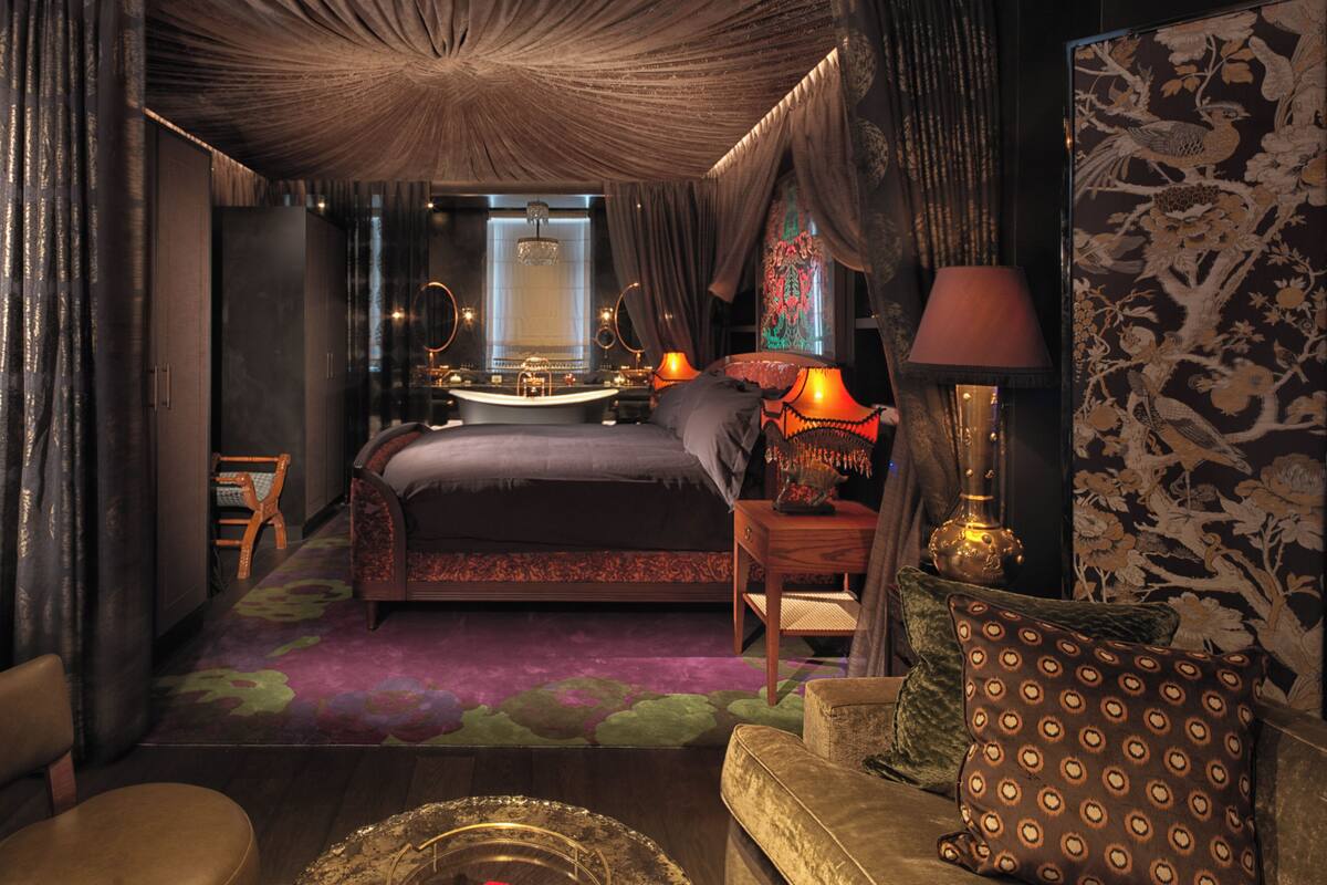 A bedroom with a large bed, a sitting area with a sofa, a small table, and a decorative lamp.