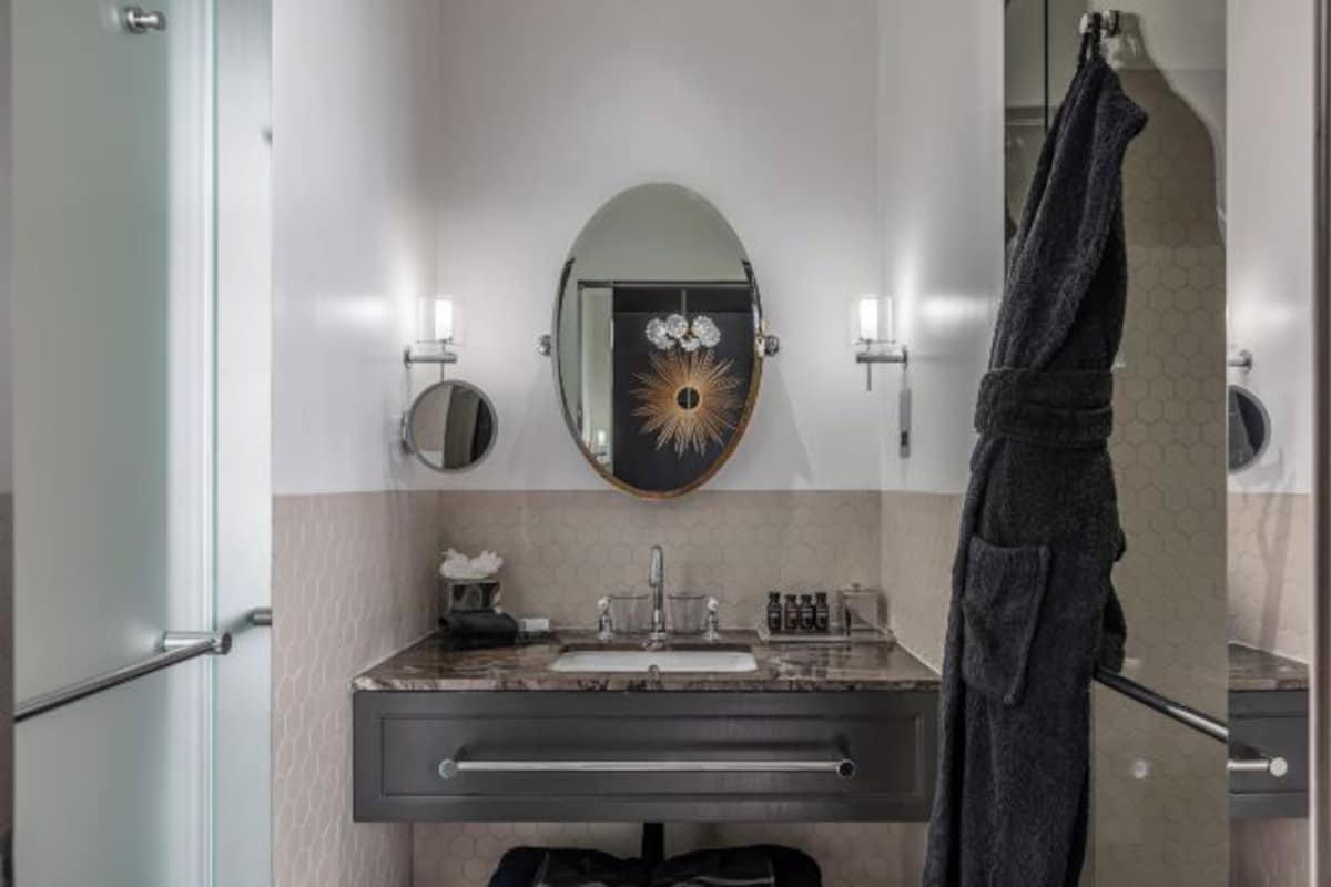 A bathroom with a vanity, a mirror, and a towel rack.