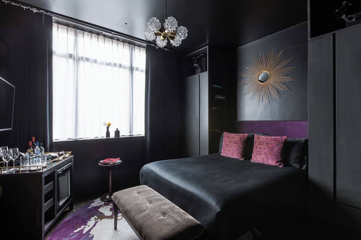 A modern bedroom with a large bed, a vanity with a mirror, and a window with curtains.
