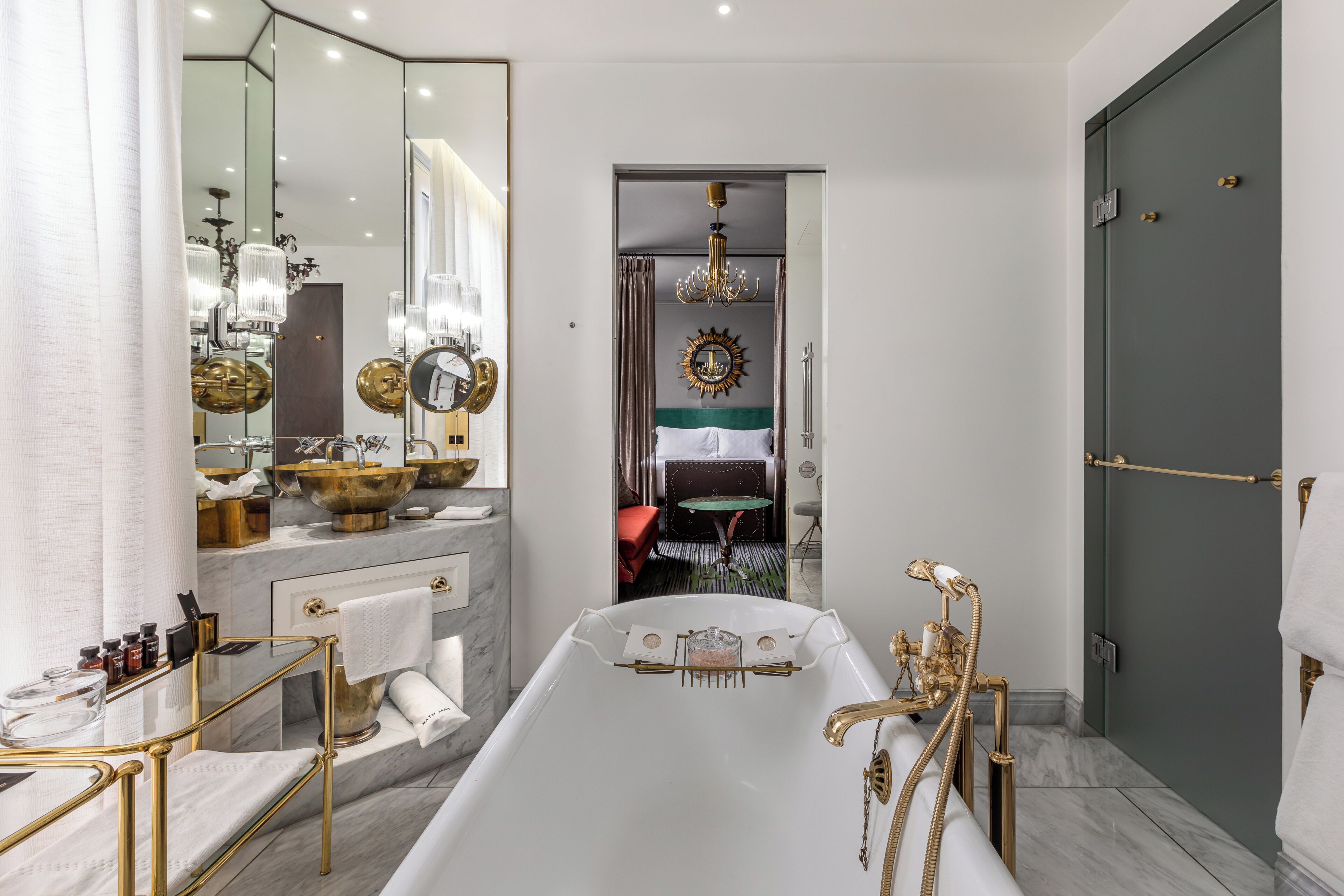 Un bagno moderno con vasca, una toeletta con uno specchio grande e un lampadario.