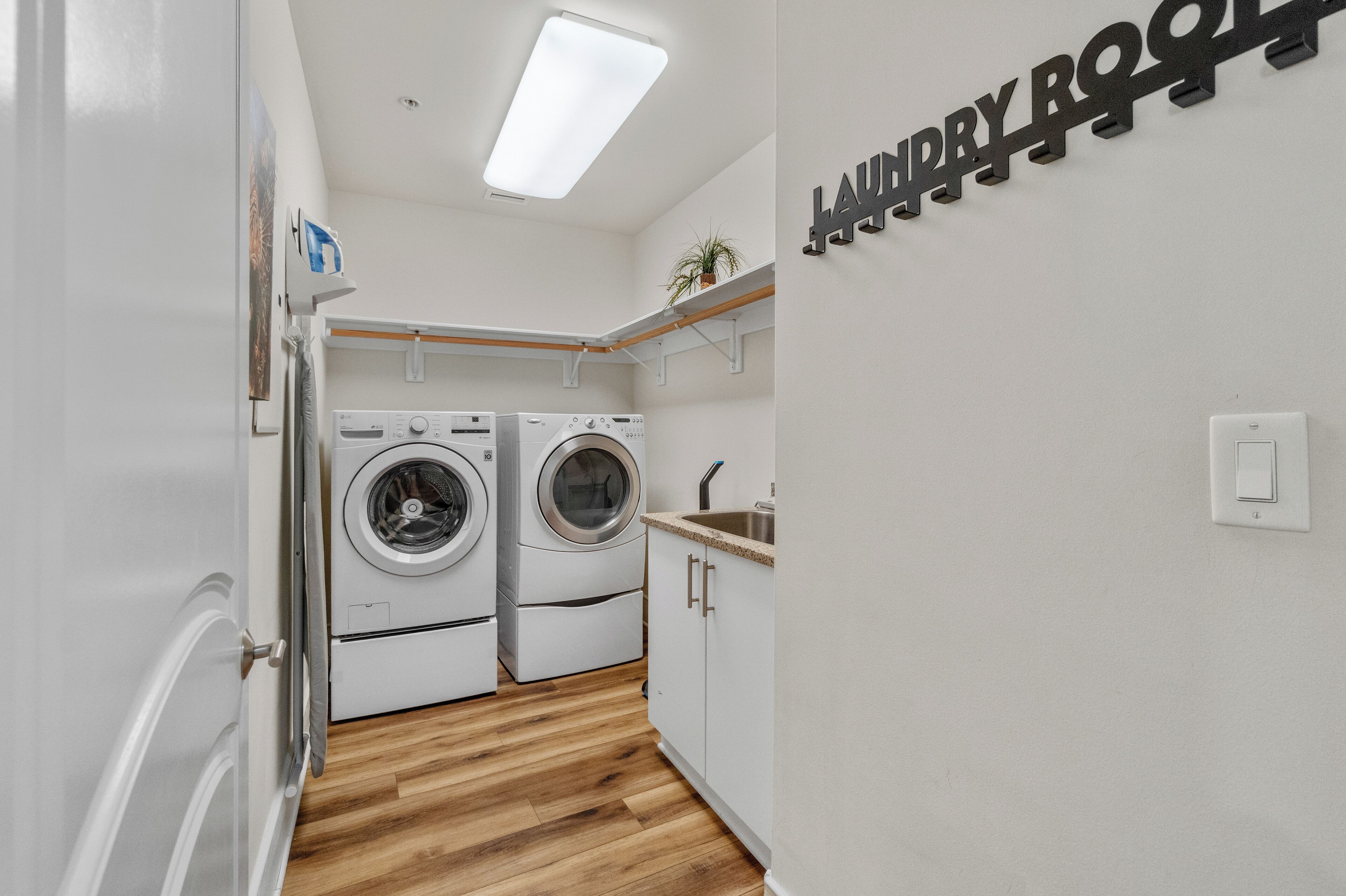 A laundry room with two washing machines, a sink, and a 'Laundry Room' sign.